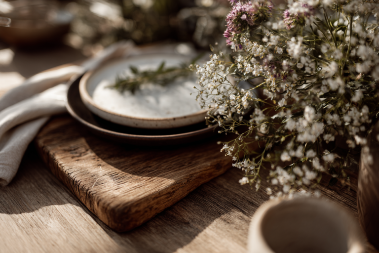 Mesa decorada com elementos naturais como flores, madeira e linho em ambiente rústico.